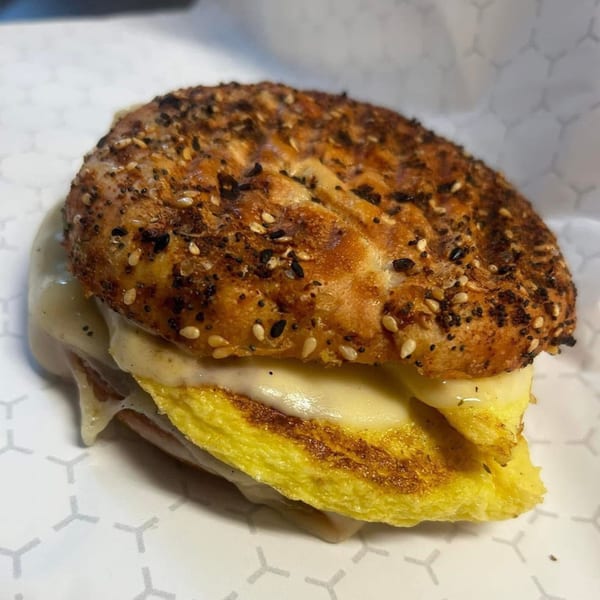 Close-up of a breakfast sandwich on an everything bagel with egg and melted cheese.