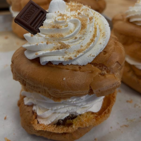 A cream puff with whipped cream, graham cracker crumbs, and a Hershey's chocolate square.