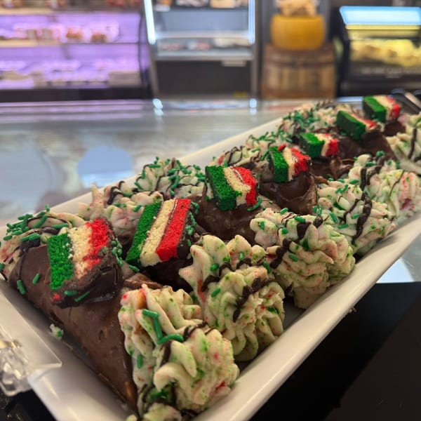 A white platter of Rocco's Market & Deli cannolis and Italian cookies with green, white, and red frosting.