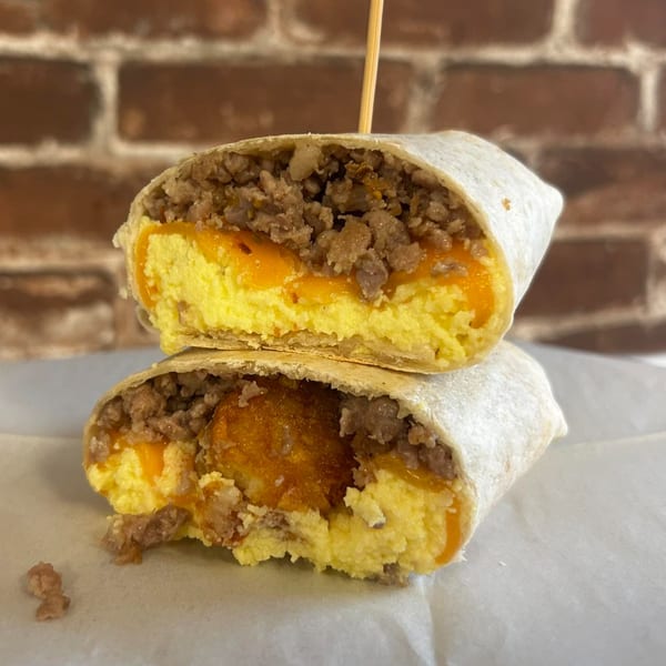 A Rocco's Market & Deli breakfast burrito, cut in half, revealing sausage, eggs, and cheese.