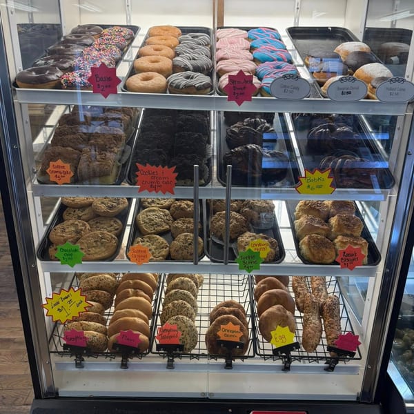 A deli display case filled with various donuts, cookies, pastries, and bagels at Rocco's Market & Deli.