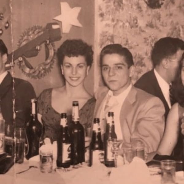 Vintage sepia photo of people at a table with beer bottles, possibly at Rocco's Market & Deli.