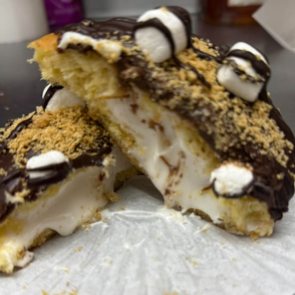 A s'mores donut from Rocco's Market & Deli, cut in half, revealing a creamy marshmallow filling.