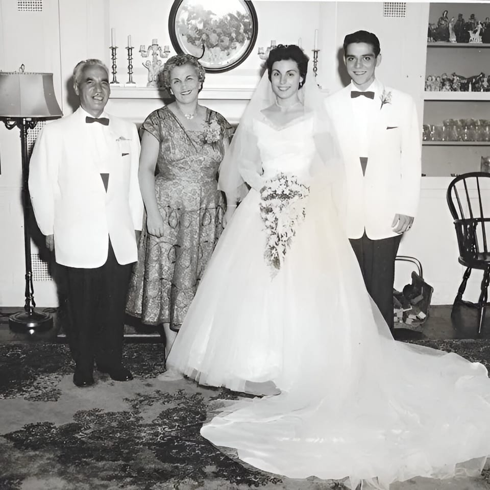 Black and white photo of a wedding party with a bride, groom, and two older adults.