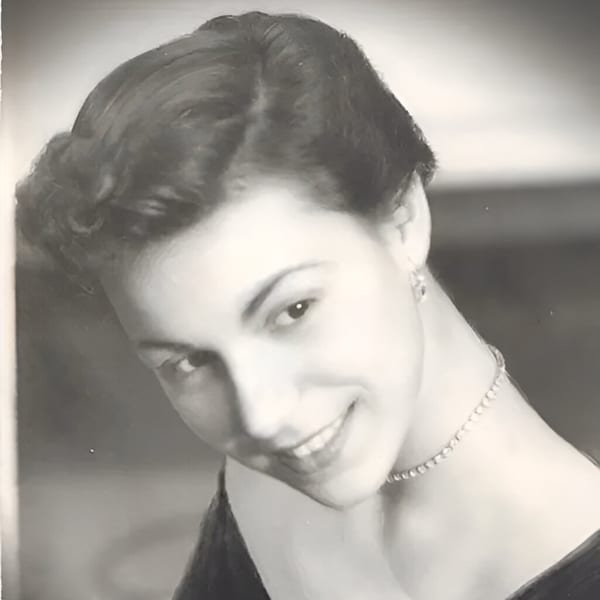 Black and white portrait of a smiling young woman with dark hair and a pearl necklace.