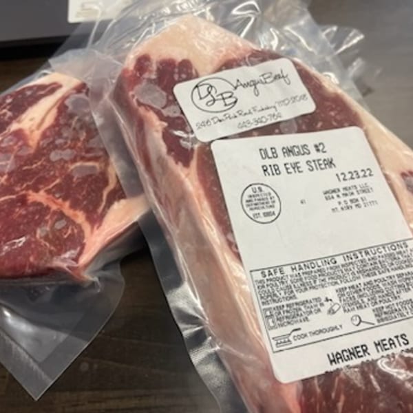 Two vacuum-sealed packages of raw DLB Angus #2 Rib Eye Steaks from Rocco's Market & Deli.